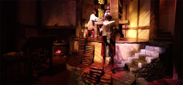 Gutenberg examines a page in front of his printing press in Spaceship Earth at Epcot.