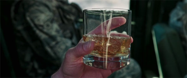 Tony Stark holds a drink while riding with a convoy right before it's attacked in the original MCU film.
