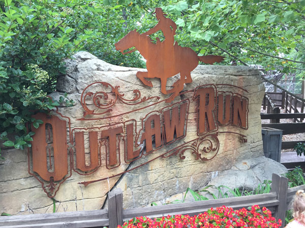 The sign for Outlaw Run at Silver Dollar City shows the details of the roller coaster's setting.