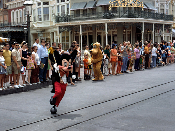 Mickey Mouse has a blast and dances around while Pluto entertains guests at the Disney parade.