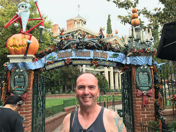 Martin Smith poses in front of Haunted Mansion Holiday at Disneyland.