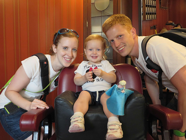 Becky from Touring Plans poses at the Harmony Barber Shop with her daughter and husband.